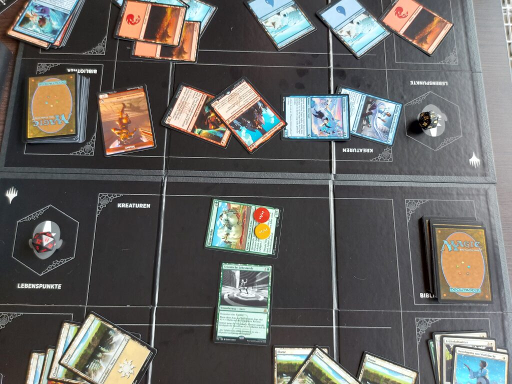 Die Karton-Spielunterlagen sind weit davon entfernt, die Qualität von professionellen Spielmatten zu haben, spielen aber ins Brettspiel-Feeling der Box hinein und sind ehrlich nützlich für neue Spieler*innen (Foto: Pascal Wagner)